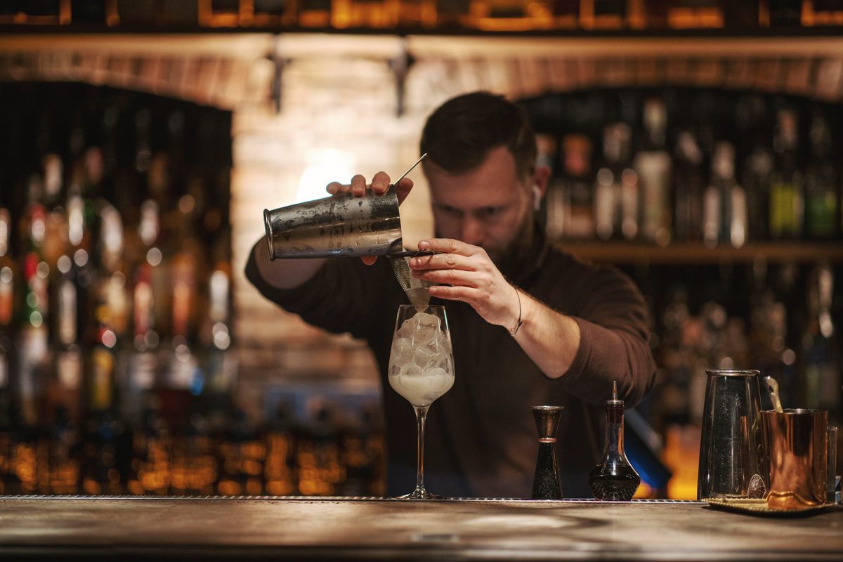 A bartender straining a drink behind the bar
